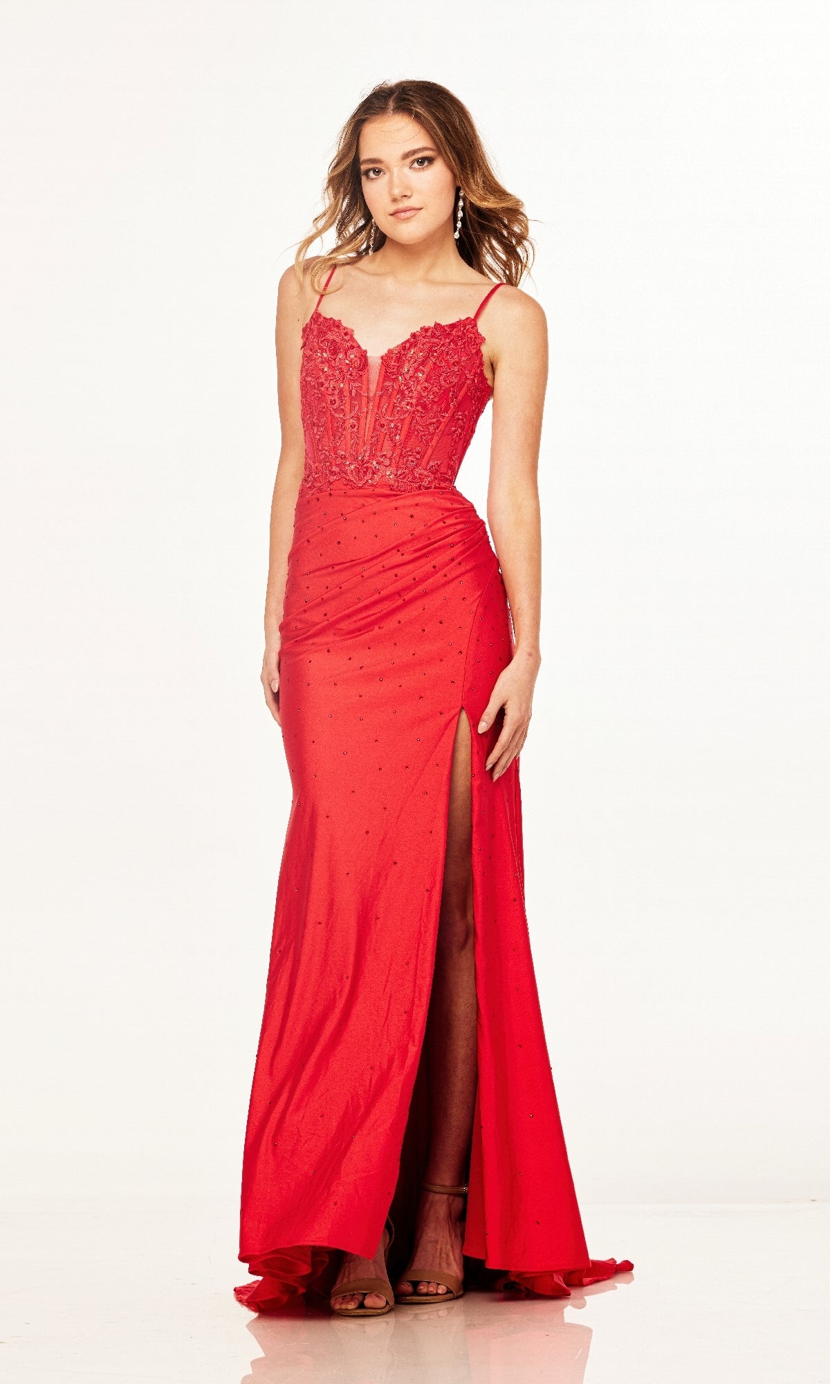 A woman models the Cecilia Couture 2601 long prom dress, featuring a red lace corset, thin straps, beaded details, and a dramatic side leg slit, standing against a plain white background.